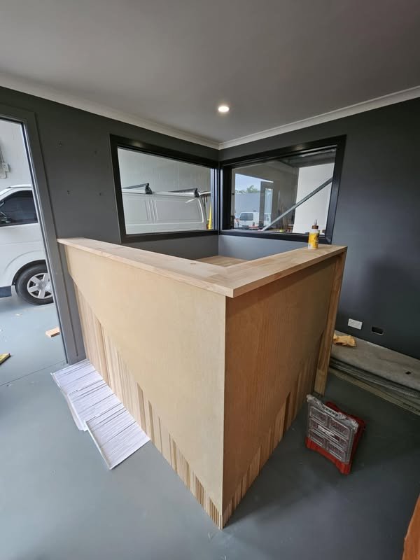 Custom fluted timber reception counter built on site by Yushin Kim