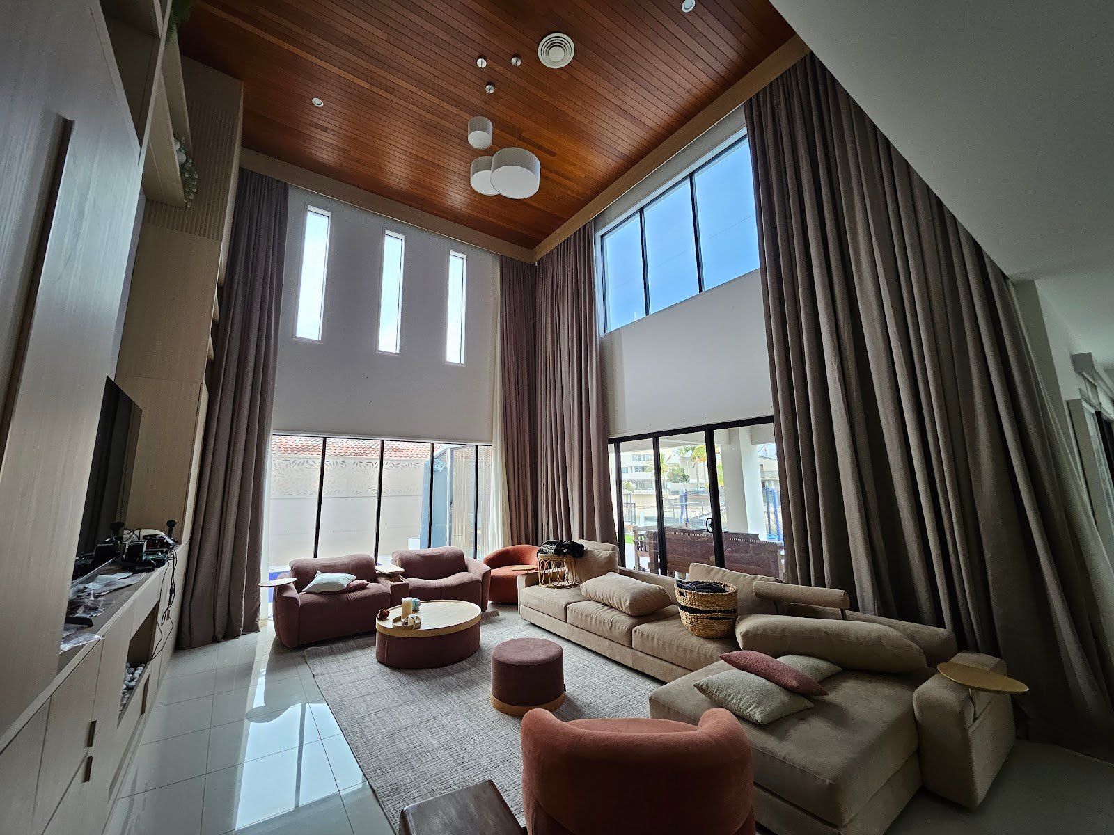 Double-height living room featuring custom timber ceiling lining and architectural media wall built by Yushin Kim on the Gold Coast